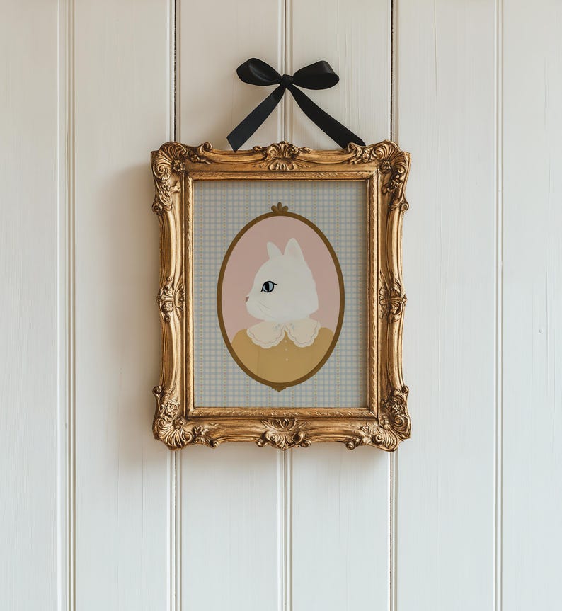 May include: A framed illustration of a white cat with blue eyes wearing a yellow collar with a white lace trim. The cat is in a pink oval frame on a blue and white gingham background.
