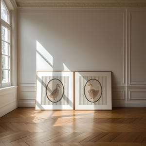 May include: Two framed prints of a brown duck with a brown bow on a white and gray striped background.