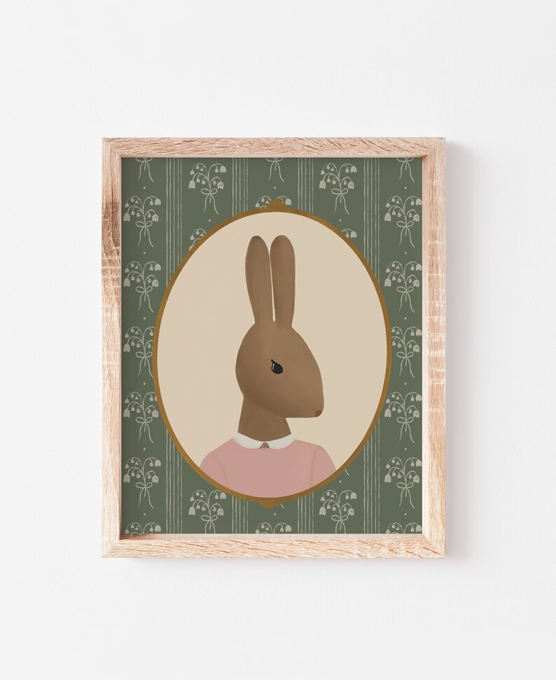 May include: A framed illustration of a brown rabbit wearing a pink shirt, set against a green background with a floral pattern.