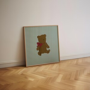 May include: A framed print of a brown teddy bear with a red bow, on a green and white gingham background.