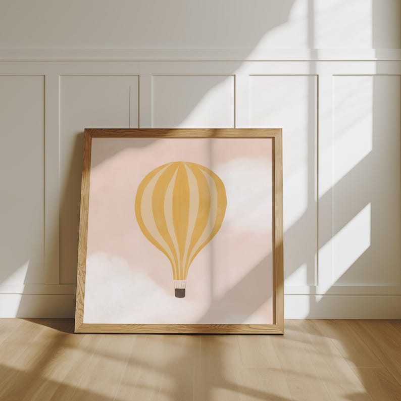 May include: A framed print of a yellow hot air balloon with white stripes against a pink background with white clouds.