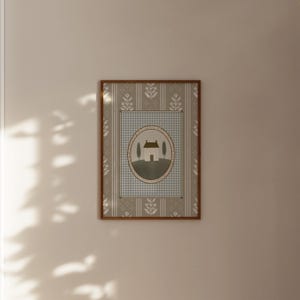 May include: A framed print with a light blue and white checkered background. The print features a white house with a brown roof and two green trees in front of it. The house is surrounded by a brown circle with a white border.