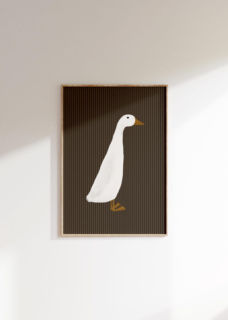 Pode incluir: Impress&atilde;o art&iacute;stica emoldurada com uma ilustra&ccedil;&atilde;o minimalista de um ganso branco com bico e patas amarelas. O ganso est&aacute; sobre um fundo castanho escuro com riscas verticais. A obra de arte est&aacute; emoldurada em madeira.