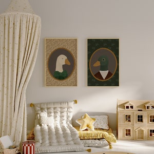 May include: Two framed illustrations of a goose and a duck wearing clothing. The goose is white with a green bow tie and the duck is green with a brown jacket and a white collar. The frames are brown and the illustrations are on a beige background.