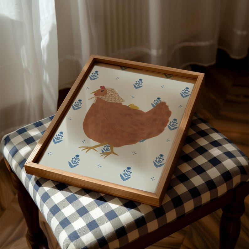 Puede incluir: Una ilustraci&oacute;n enmarcada de una gallina marr&oacute;n con un fondo de patr&oacute;n floral azul y blanco. La gallina lleva un gorro de patr&oacute;n azul y blanco y tiene un pollito amarillo en la espalda.
