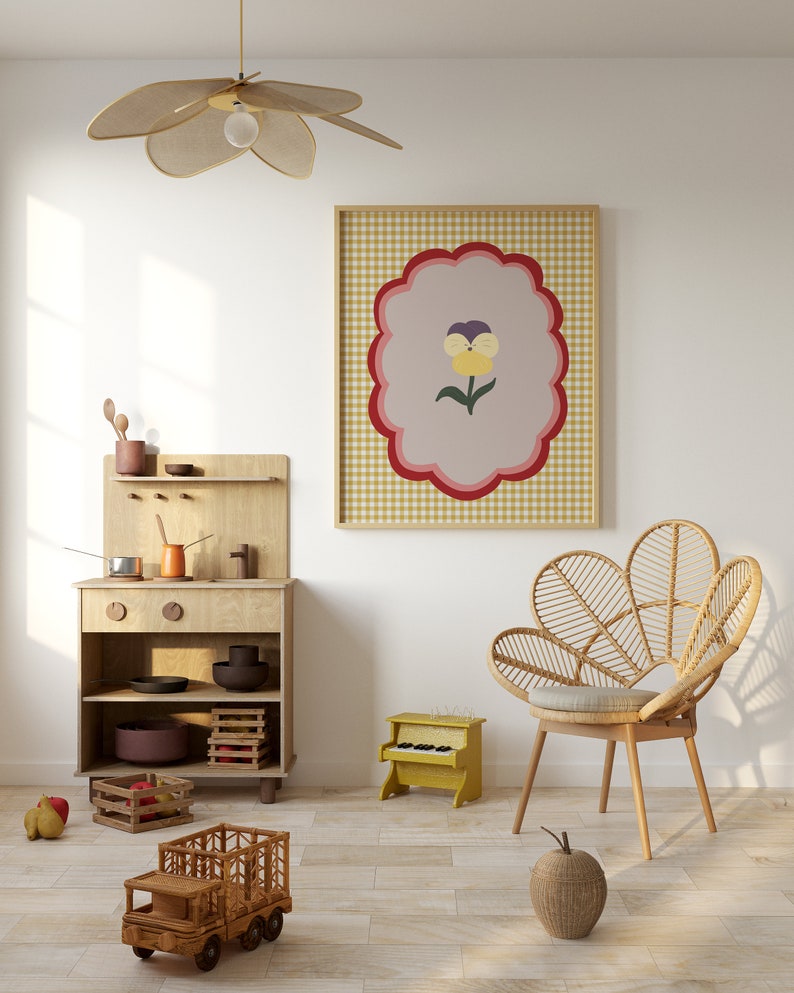 May include: A light wood play kitchen with a toy stove, oven, and shelves. A toy truck, a toy piano, and a wicker chair are in the room. A framed print with a yellow flower on a pink and white checkered background hangs on the wall.