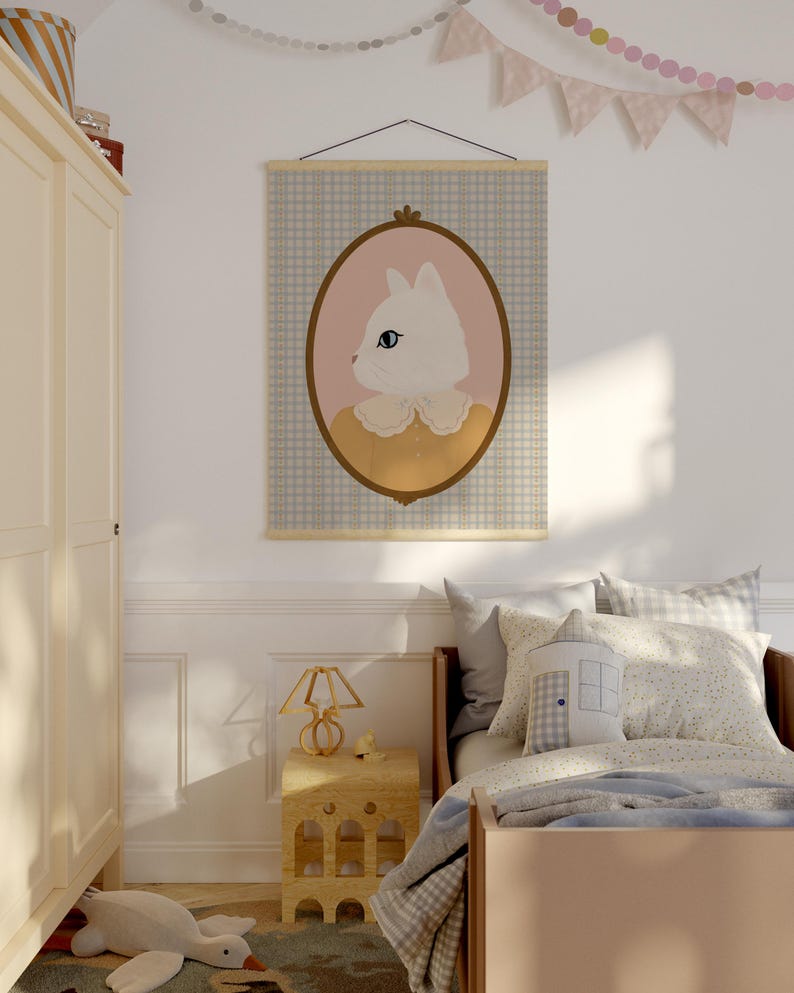 May include: A white cat with blue eyes in a yellow dress is framed in a brown oval and displayed on a blue and white checkered wall tapestry. The tapestry is hanging on a wooden rod.