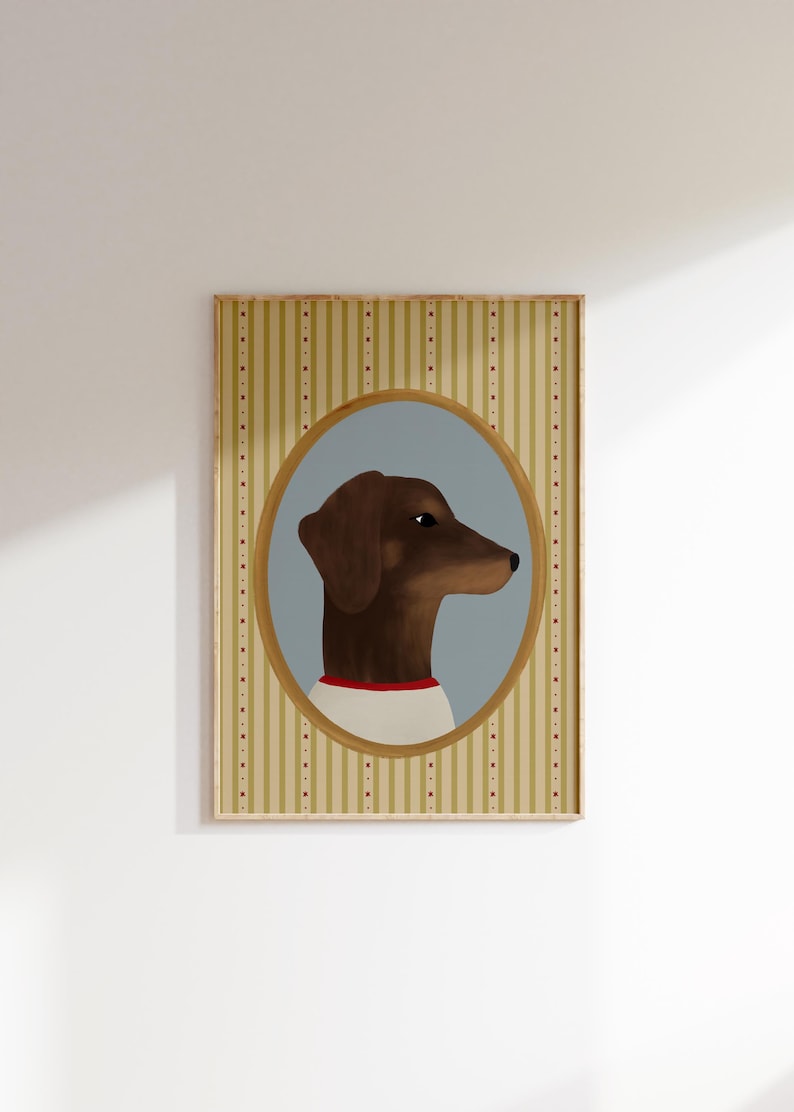 May include: A framed portrait of a brown dachshund dog in profile, set against a light blue oval. The dog wears a white shirt with a red collar. The background is a striped pattern in beige and gold with red dots.