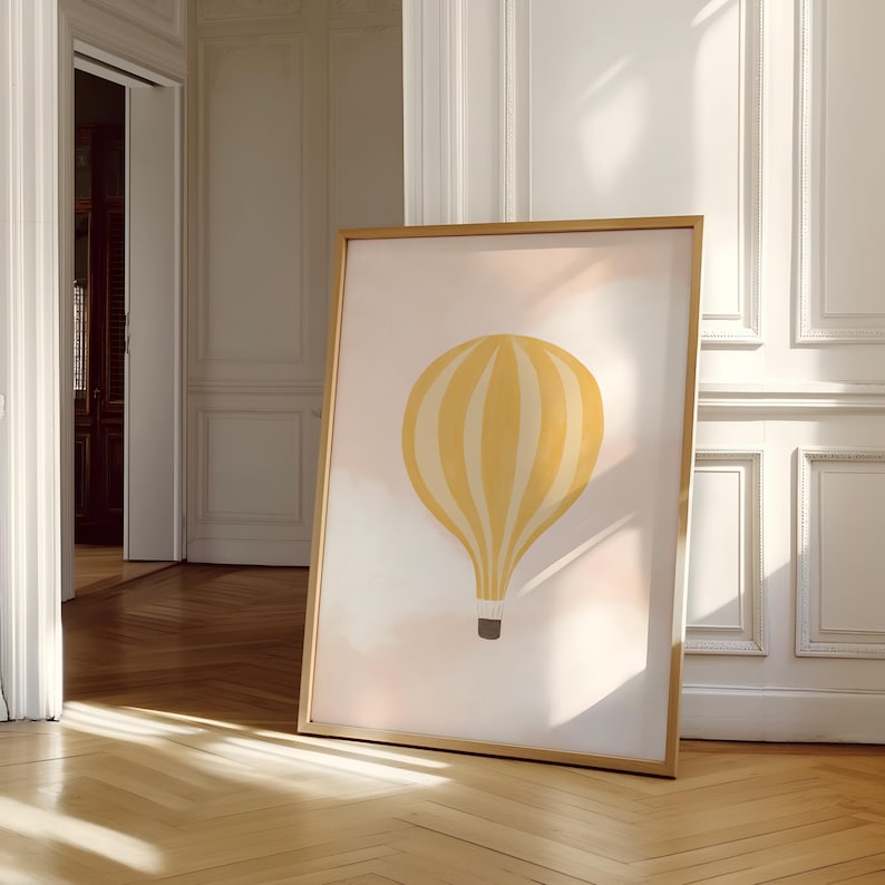 May include: A framed print of a yellow and white striped hot air balloon against a pink and white background. The balloon is floating in the sky with clouds.