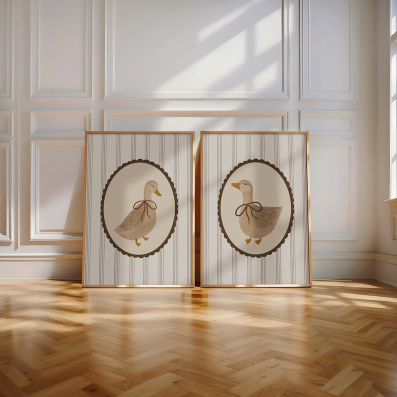 May include: Two framed prints with a striped background and a brown oval frame. Each frame features a watercolor illustration of a duck with a brown bow tie.