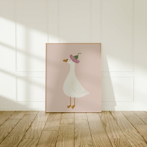 May include: A framed illustration of a white goose wearing a pink flower on its head. The goose is standing on a pink background.