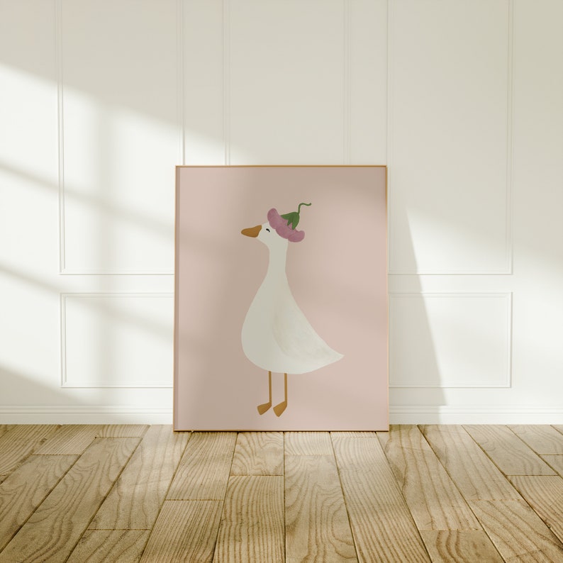May include: A framed illustration of a white goose wearing a pink flower on its head. The goose is standing on a pink background.