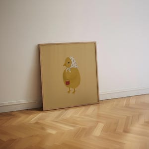 Puede incluir: Una ilustraci&oacute;n enmarcada de un pollito amarillo con un pa&ntilde;uelo de cabeza estampado en azul y blanco y sosteniendo un peque&ntilde;o cubo rojo.