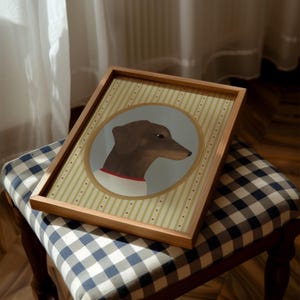 May include: A framed print featuring a brown dachshund dog in profile, set against a light gray background within a circular frame. The print has a striped background with a wooden frame. The dog wears a white collar with a red band.