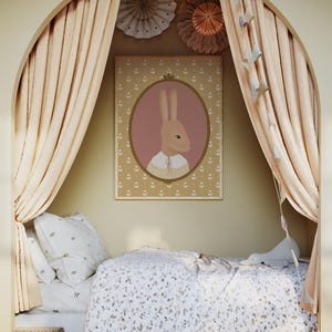 May include: A light brown bunny with a pink oval frame around it is on a poster with a light brown background. The poster is hanging on a wall in a room with a bed and curtains. The bed has a white and brown patterned duvet and a white pillow with a small pattern. The curtains are a light brown color and are pulled back to reveal the bed.