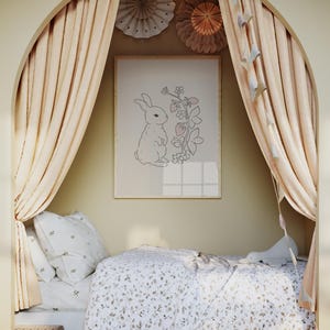 May include: A white bed with a floral patterned duvet cover and a white pillow with a floral pattern. The bed is in a nook with beige curtains and a framed print of a rabbit with strawberries.