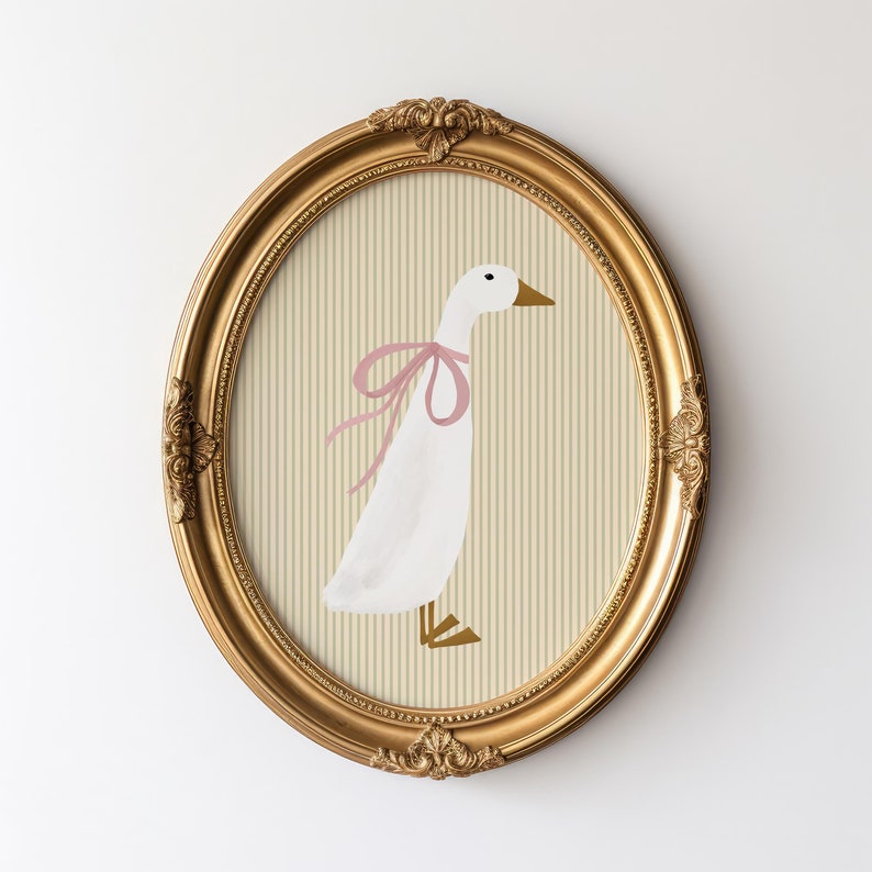 May include: A framed illustration of a white goose with a pink bow, set against a striped background of beige and cream.