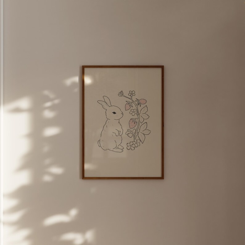 May include: A framed print of a white rabbit standing next to a line drawing of a strawberry plant with pink strawberries.
