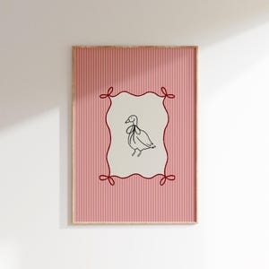 May include: A framed print with a pink and white striped background. A red ribbon frame surrounds a black and white line drawing of a bird with a bow tie.