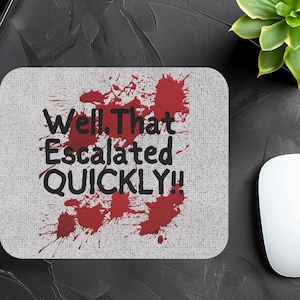 May include: A white mouse pad with red splatter paint and the text "Well, That Escalated QUICKLY!" in black.