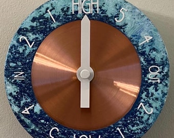 May include: A round, blue and white clock with a copper face. The clock has a white hand pointing to the word "HIGH" and numbers 1 through 5 around the outer edge. The words "LOW" and "IN" and "OUT" are also visible on the clock.