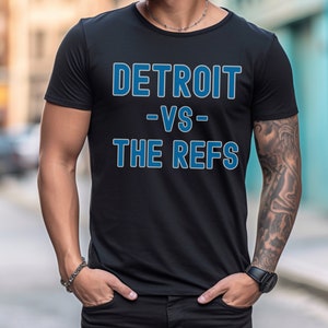 Könnte beinhalten: Schwarzes T-Shirt mit blauem Text, der "DETROIT -VS- THE REFS" lautet.