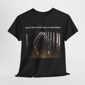 Op de afbeelding: Zwart T-shirt met een afbeelding van een lange, dunne, humanoïde figuur met een grote mond en lange armen. De tekst "don't think that was a microdose" is boven de afbeelding gedrukt.