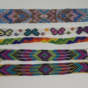 May include: Five colorful beaded bracelets with different patterns. The bracelets are made with small, colorful beads and have metal clasps.