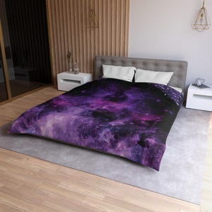 May include: Purple and black galaxy print duvet cover with a white and gray bed frame.