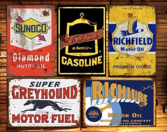 Puede incluir: Cinco letreros metálicos vintage con un aspecto rústico y desgastado. Los letreros anuncian varios aceites y combustibles para motores, incluyendo Sunoco Diamond Motor Oil, Motorpower Gasoline, Richfield Motor Oil, Super Greyhound Motor Fuel y RichLube Motor Oil. Los letreros se muestran en una pared de madera.