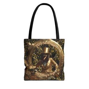 May include: Black tote bag with a gold and black design. The bag features a gold frame with the text "2026 Has Arrived And Rolling In Style". Inside the frame is a figure in a gold suit and top hat with the number 7 on its face.