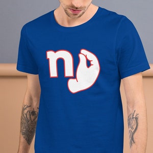 May include: A royal blue t-shirt with a white graphic of the letter "n" and a white hand making the "okay" sign. The hand is outlined in red.