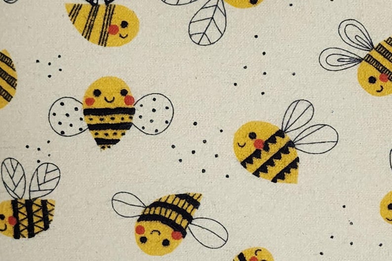 May include: A repeating pattern of cartoon bees on a cream-colored background. The bees are yellow with black stripes, dotted wings, and smiling faces. Small black dots are scattered around the bees.