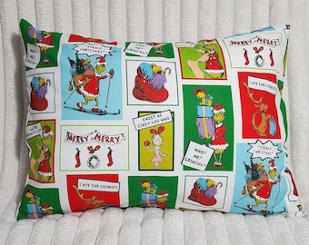 Pode incluir: Uma fronha retangular com fundo branco e uma estampa repetitiva em estilo de banda desenhada do Grinch, do cão Max e da Cindy-Lou Who. As ilustrações coloridas incluem balões de texto como "Steals Christmas", "Who? Me? Grinchy?" e "Merry Merry".