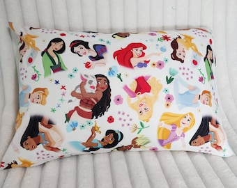 May include: White rectangular pillow featuring colorful illustrations of various princesses. The design includes images of Snow White, Ariel, and Jasmine, among others, with floral and botanical accents. The pillow is set against a white, textured background.
