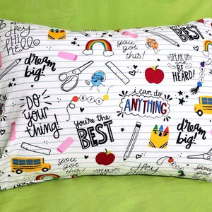 May include: White pillowcase with a school-themed design. Features illustrations of pencils, scissors, apples, rainbows, and school buses. Includes text like "dream big!" and "you got this!"
