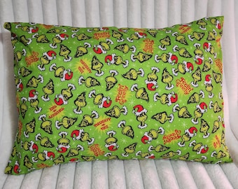 May include: Green pillowcase with a repeating pattern of a yellow character wearing a red Santa hat. The words "Naughty or Nice" and "Feelin' Grinchy" are also printed on the pillowcase. The pillowcase is rectangular.