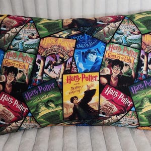 Könnte beinhalten: Rechteckiges Kissen mit einer Collage von Harry Potter Buchcovern. Die Cover zeigen verschiedene Farben, darunter Rot, Grün und Blau, mit Bildern von Harry Potter und anderen Charakteren. Ein dekorativer Artikel für Fans.