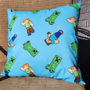 May include: A blue pillowcase with a repeating pattern of green Minecraft characters, including Steve and Creepers.