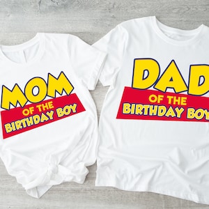 Puede incluir: Dos camisetas blancas con un dise&ntilde;o gr&aacute;fico amarillo y azul. El texto en las camisetas dice "Mom of the Birthday Boy" y "Dad of the Birthday Boy".