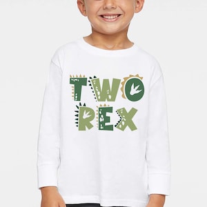 May include: White long-sleeved shirt with green and brown dinosaur footprints and the text "TWO REX" on the front.