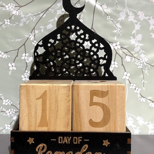 May include: A wooden countdown calendar with a black mosque silhouette on top. The calendar is set to day 15 of Ramadan.