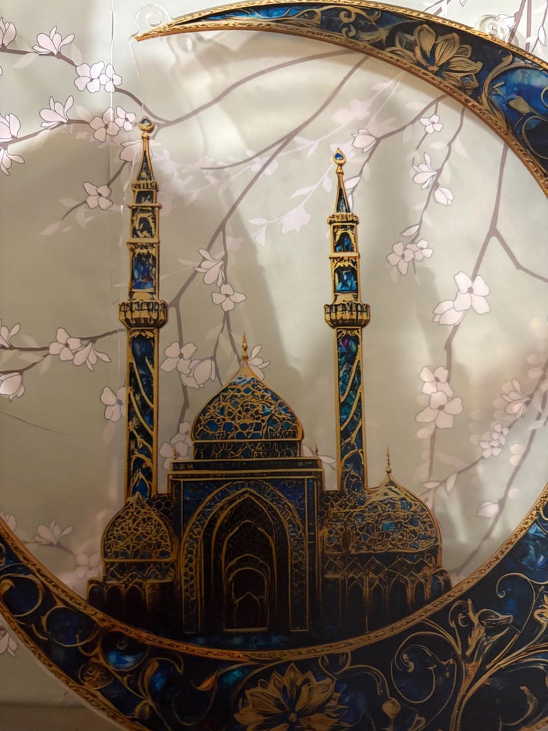May include: A gold and blue crescent moon with a detailed design, featuring a mosque with two minarets and intricate details. The background is a light green with white flowers.