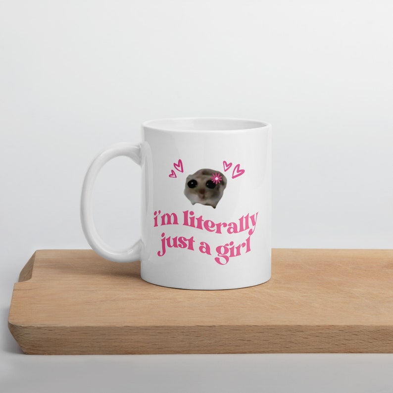 Pu&ograve; includere: Una tazza in ceramica bianca con un design rosa e bianco. La tazza presenta un'immagine di un piccolo animale con un fiore sulla testa. Il testo "i'm literally just a girl" &egrave; stampato in rosa sulla tazza.