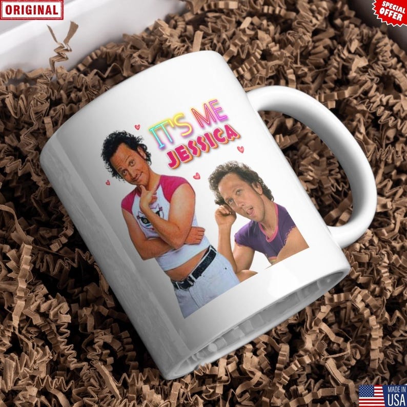 May include: White ceramic mug featuring a colorful graphic of a person with the text "IT'S ME JESSICA" and small pink hearts. The mug has a curved handle and is surrounded by brown packing material.