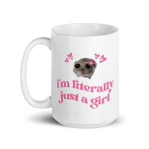 Pu&ograve; includere: Tazza in ceramica bianca con un design rosa. Il design presenta un piccolo animale con un fiore sulla testa, circondato da cuori. Il testo "i'm literally just a girl" &egrave; scritto in rosa sotto l'animale.