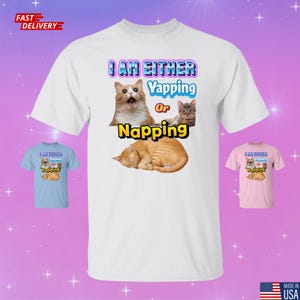 May include: White t-shirt featuring a graphic of three cats and the text "I AM EITHER Yapping Or Napping" in blue and yellow. The shirt also has a small image of a cat on a light blue and pink shirt.