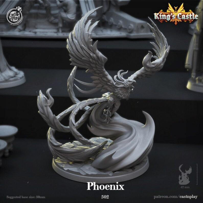 May include: A gray 3D printed miniature of a phoenix in flight. The phoenix has detailed wings, a long tail, and a fierce expression. The miniature is on a round base with a textured surface. The text "Phoenix 502" is printed below the miniature.