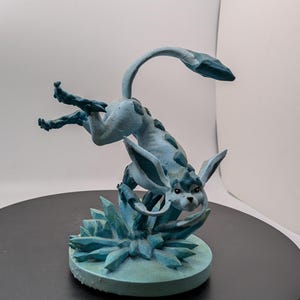 May include: A blue and white painted figurine of a mythical creature with a long tail and large ears, standing on a base of ice crystals.