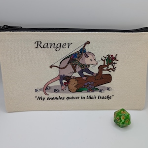 May include: A white canvas zippered pouch with a black zipper. The pouch has a printed image of a possum with a bow and arrow, standing on a log. The text "Ranger" and "My enemies quiver in their tracks" is printed on the pouch.
